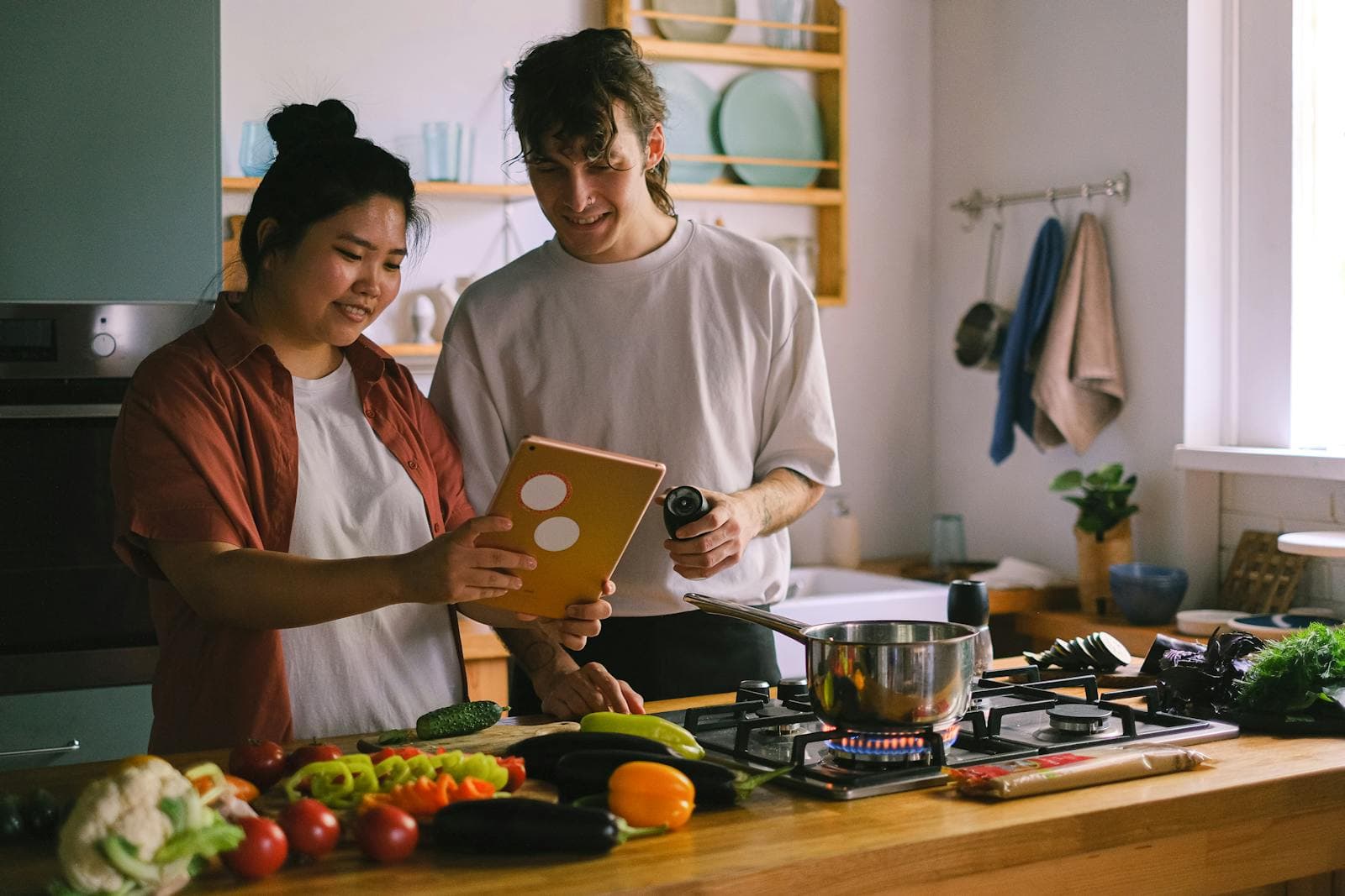 Couple cooking together in a modern kitchen, browsing recipes on a tablet